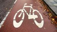 biały namalowany znak roweru na czerwonym gruncie