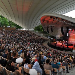 obrazek przestawia Amfiteatr w Koszalinie pełen publiczności podczas występu na scenie - widok od wewnątrz, zdjęcie w kolorze wykonane z górnych stopni amfiteatru 