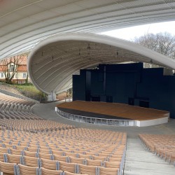 obrazek przestawia pusty Amfiteatr w Koszalinie ( bez publiczności ) - zdjęcie w kolorze, ukazuje siedziska i scenę, wykonane z górnych stopni amfiteatru 