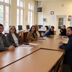 obrazek w kolorze przedstawiający stół w sali konferencyjnej przy nim dziewięć osób - nauczycieli wraz z dyrektorem podczas szkolenia matematyków 
