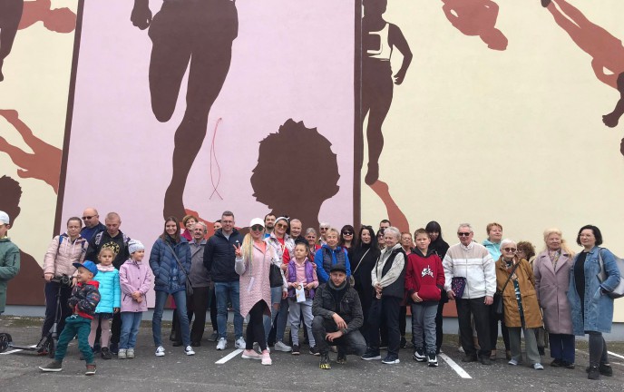 Zdjęcie przedstawia uczestników spaceru na tle znanego muralu pt. "Maratończyk", ukazującego biegaczy