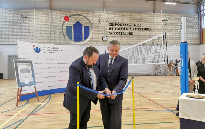 Prezydent Miasta Koszalina przecinający wstęgę na uroczystości w wyremontowanej hali sportowej koszalińskiego "Ekonoma"