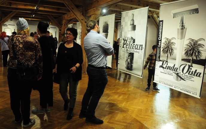 Uczestnicy wystawy na tle prezentowanych czarno - białych plakatów.
