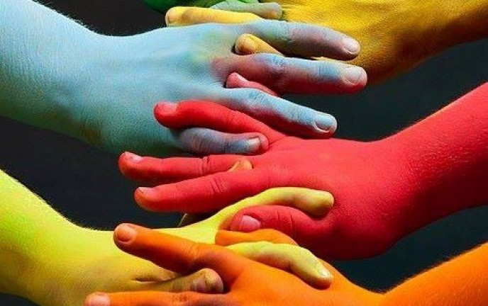 Grafika przedstawia splecone razem dłonie w kolorach tęczy.