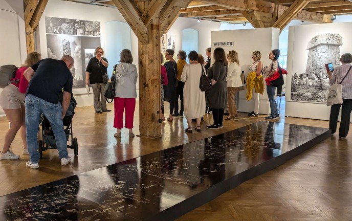 Zdjęcie przedstawia osoby zwiedzające wystawę w sali Muzeum w Koszalinie
