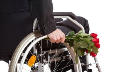 Na zdjęciu osoba na wózku inwalidzkim z bukietem róż 