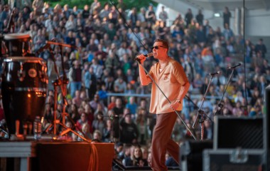 Na zdjęciu wokalista Mrozu na tle zapełnionego publicznością Amfiteatru.