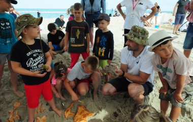 Zdjęcie przedstawia dzieci podczas "wykopalisk" na plaży
