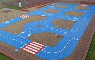 obrazek przedstawia miasteczko ruchu drogowego ( kolorowa plansza na boisku szkolnym) przy Szkole Podstawowej nr 13 w Koszalinie